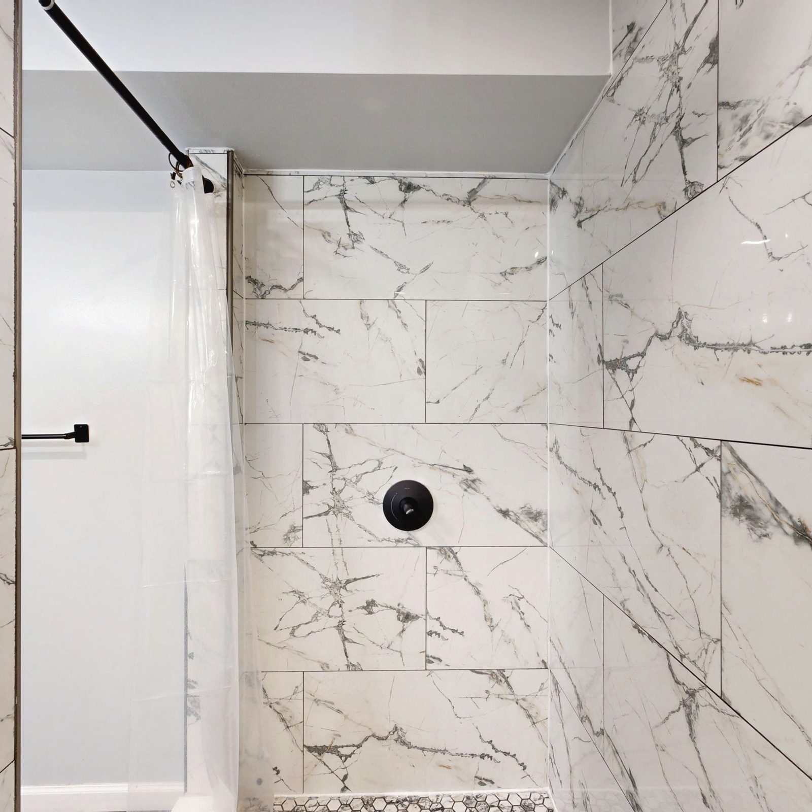 White marble-look tiled shower with black fittings