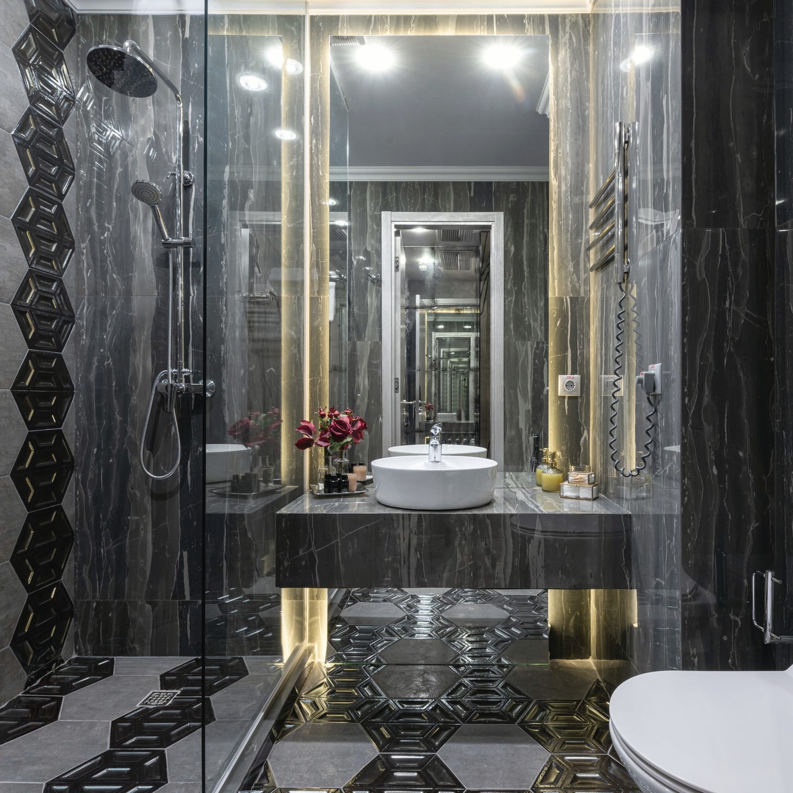 Black stone bathroom with a lit mirror and patterned floor