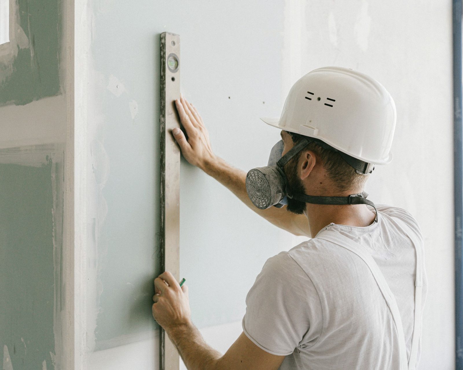 Worker in a helmet fitting a plasterboard sheet