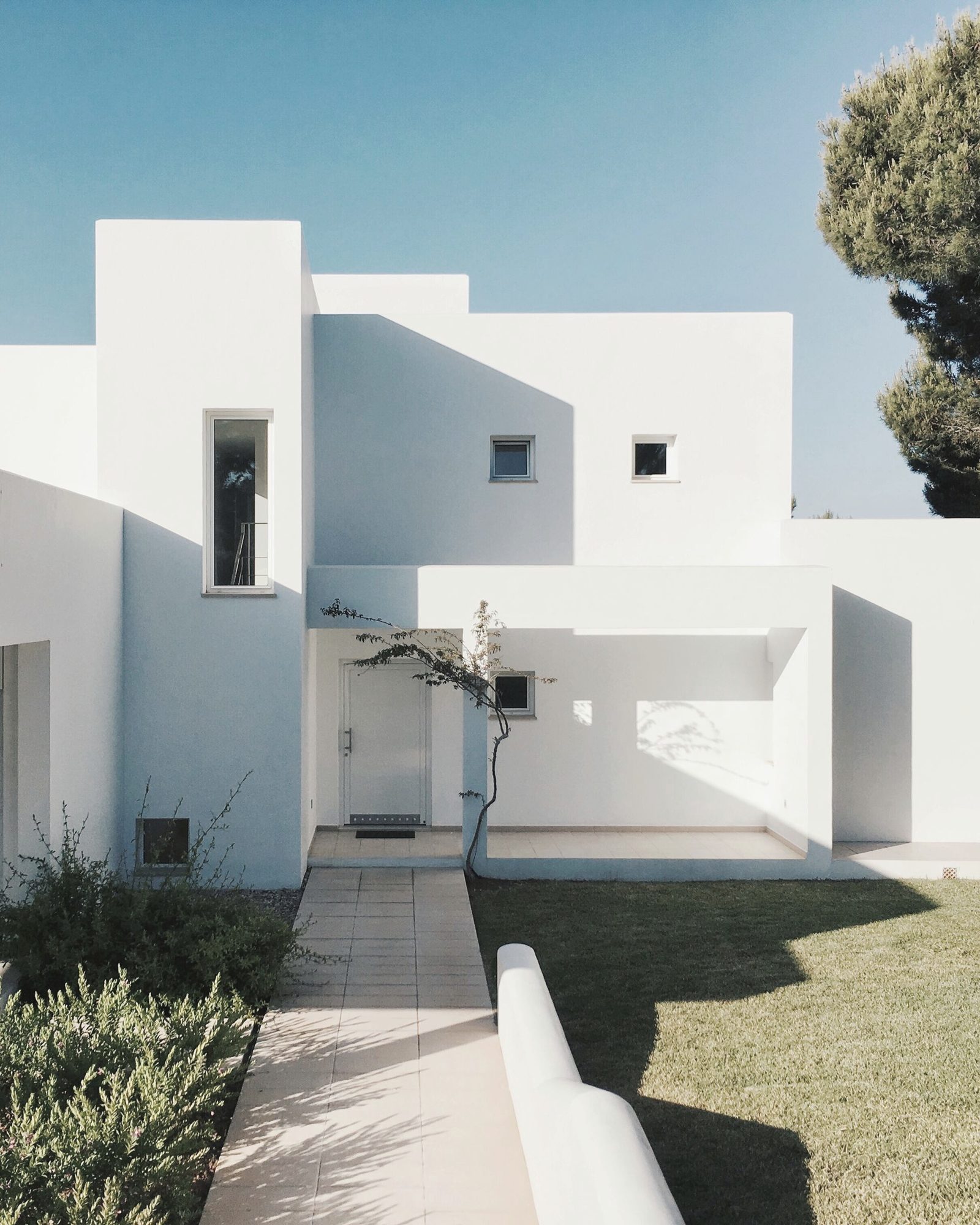 White modern private house with a garden and pine trees
