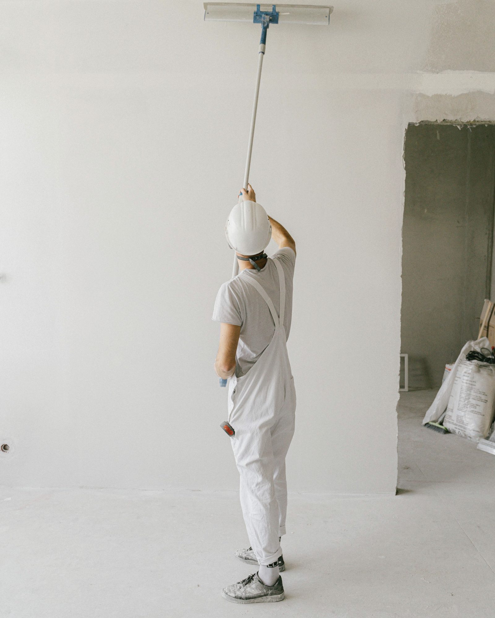 Painter rolling white paint onto a high wall